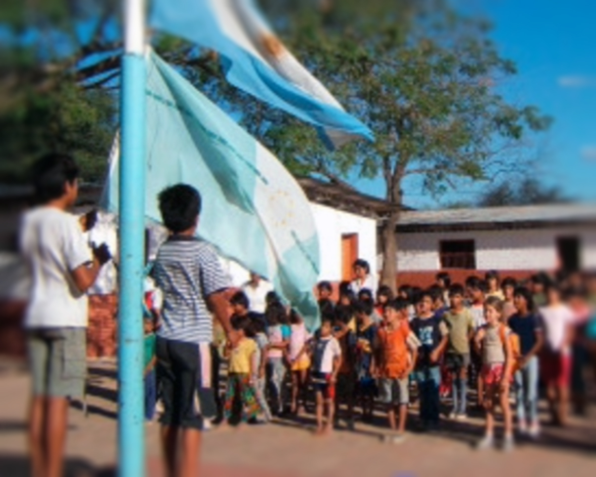 Imagen típica de escuela rural argentina. Niños formados frente a la bandera.